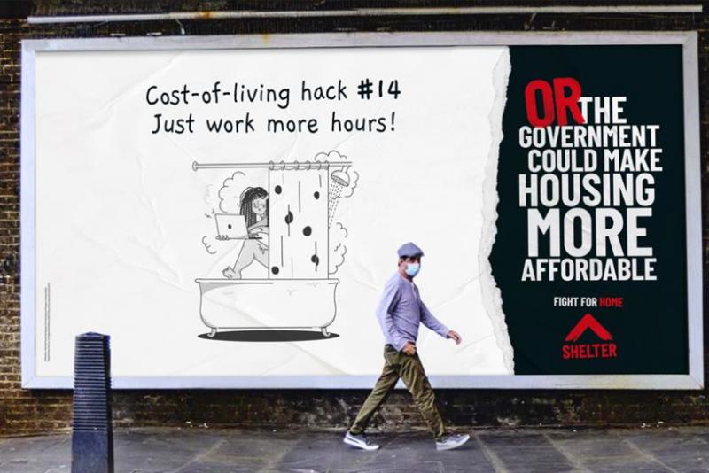Billboard with a picture of someone working whilst in the shower that says 'Cost of Living Hack #14' - Just work more hours OR THE GOVERNMENT COULD MAKE HOUSING AFFORDABLE