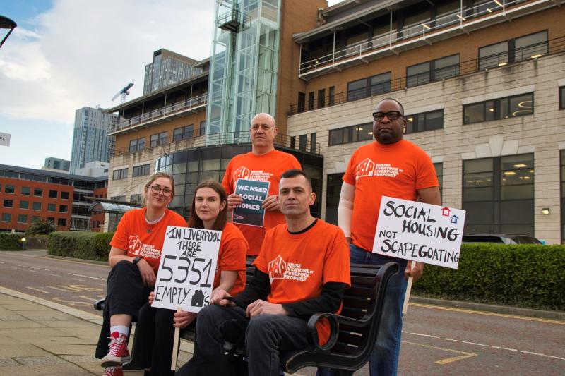 House Everyone In Liverpool Properly (HELP) activists dressed in orange, holding signs reading 'Social Housing Not Scapegoating' and 'In Liverpool there are 5351 Empty Homes'
