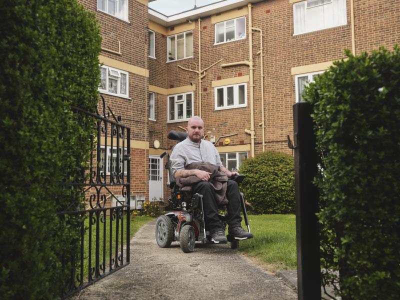 Stephen, a wheelchair user and housing campaigner, outside their home